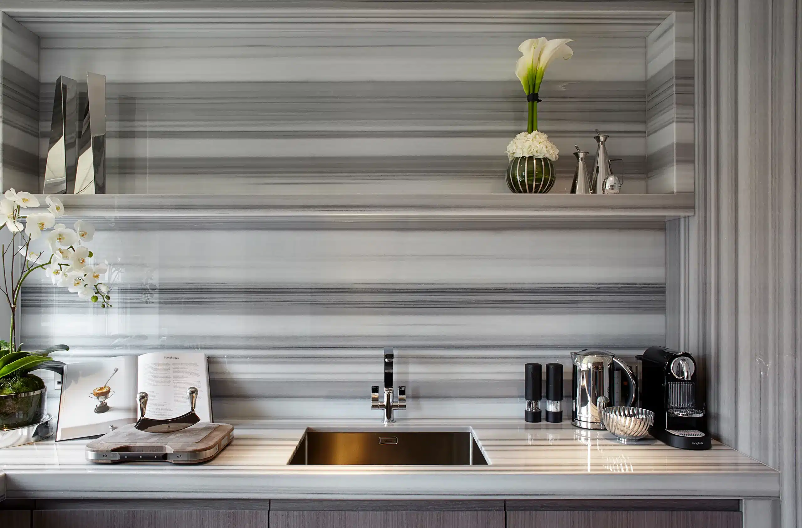 a kitchen with striking grey, black and white splashback that carries down to the benchwork