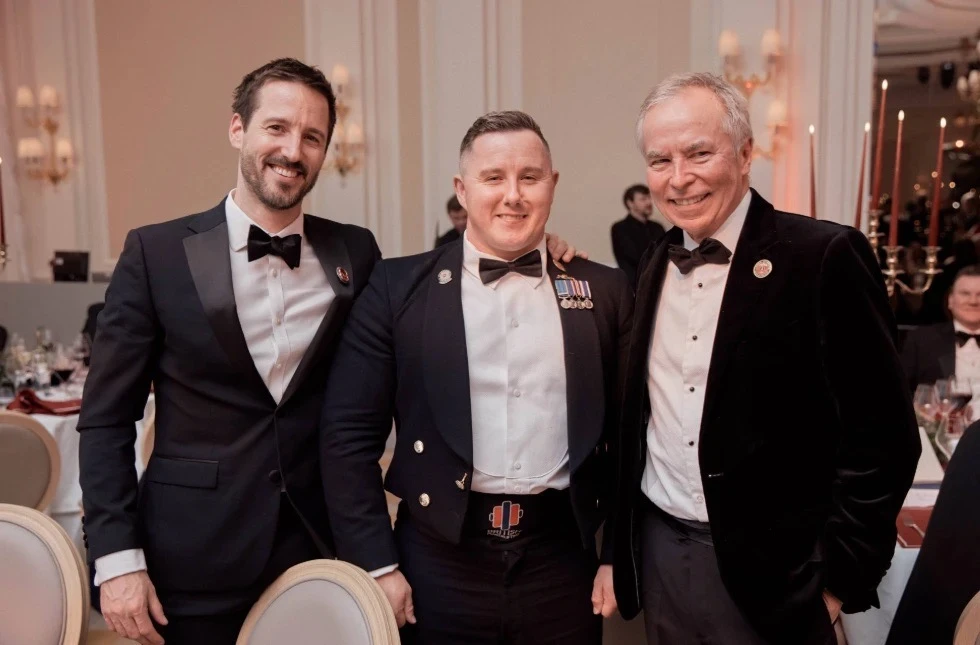 Three men in formal dress smile for the camera